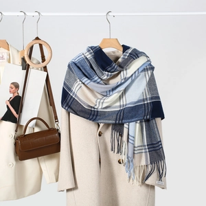 Detail of classic plaid scarf with tassel edges and hand made label on beige wool coat