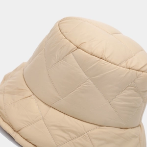Detailed macro view of diamond quilted stitching on the beige winter bucket hat fabric