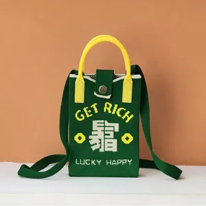 Macro shot of dark green knitted phone bag with Lucky Happy yellow handles and embroidery