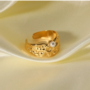 Macro detail of molten texture golden ring with a white pearl on silk fabric