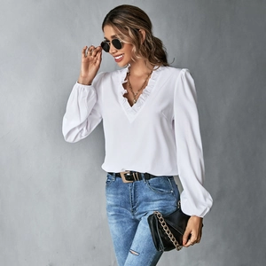 Detail einer weißen V-Ausschnitt-Bluse mit Rüschen und elastischen Ärmelbündchen