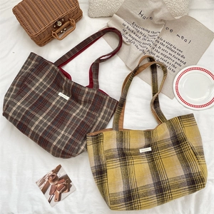 Flat lay detail of vintage plaid tote bag with brand label and picnic accessories