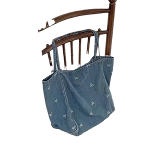 Blue denim tote bag with white bow embroidery and spacious shoulder strap design