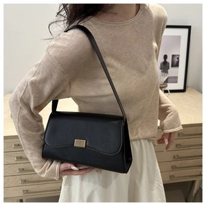 Side view of a woman wearing a black leather baguette bag with a gold buckle