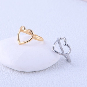 Minimalist gold and silver heart open rings displayed on a white textured stone surface