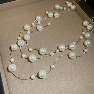 Detail of elegant gold-toned multi-layer necklace with lustrous white pearls on velvet