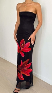 Détail d'une robe longue bustier noire avec un imprimé floral rouge vif sur le bas de l'ourlet