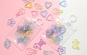 Close-up of colorful heart and star shaped metal paper clips in clear plastic packaging