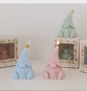 Close-up of cute gnome scented candles in blue, pink, and green with gift packaging