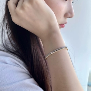 Close-up of gold and silver tennis bracelets with sparkling zircons on a model's wrist
