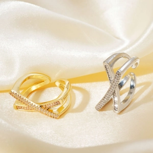 Close-up of elegant crossover micro-pave zircon rings on beige silk fabric background