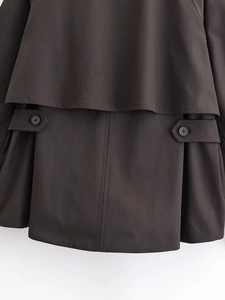 Dettaglio del trench marrone scuro con patta frangivento e cinturino in vita con bottone
