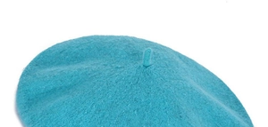 Detail shot of the lake blue beret top featuring a classic small tail on knit fabric