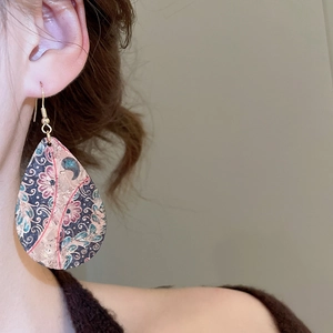 Detail of teardrop leather earrings with vintage floral print worn by a female model