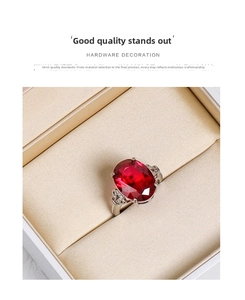 Close-up of an oval red gemstone ring with side diamonds in a silk jewelry box