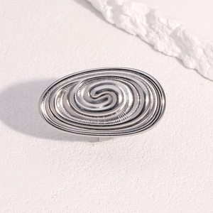Macro detail of silver spiral texture ring on white textured surface with rope accent