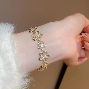 Detailed view of a gold flower bracelet with sparkling zircon stones worn on the wrist