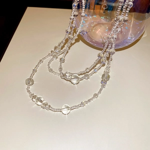 Detailed view of multilayer transparent glass bead necklace on a neutral surface