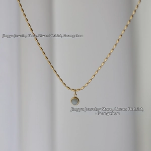 Macro detail of round grey aventurine stone pendant on 18K gold plated chain
