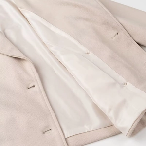 Detail of soft beige wool coat showing smooth satin lining and high-quality fabric texture