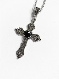 Close-up of vintage silver cross necklace with black gemstone and embossed details