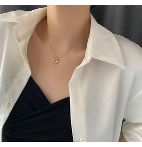 Close-up of a gold moon pendant necklace with a small sparkling stone on a model