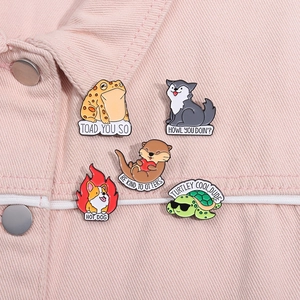 Close-up of five cartoon animal enamel pins with pun text on pink denim jacket