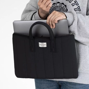 Detailed view of black quilted laptop bag with sturdy handles and woven label