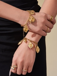 Gros plan détaillé de l'ensemble bracelet à breloques cœur et bagues en acier doré 18k