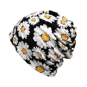 Detail of white daisy floral print on black knit beanie with soft elastic fabric texture