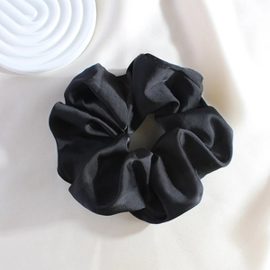 Close-up of a premium black satin scrunchie featuring an elegant glossy silk texture