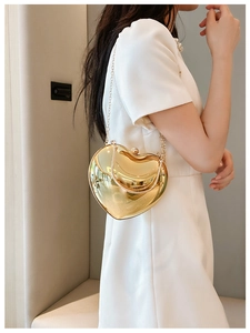 Close-up of gold heart-shaped acrylic handbag with elegant metal chain and glossy finish