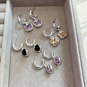 Detailed macro view of S925 silver butterfly and heart pendant earrings on a tray