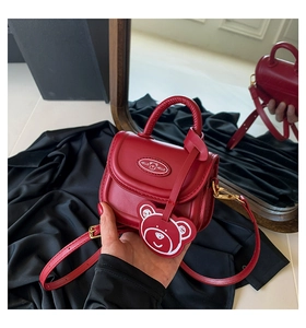 Close-up of a red mini handbag with a cute bear charm and reflective mirror view