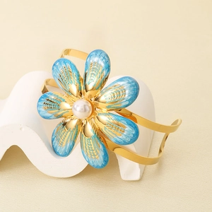 Detail of gold flower bangle with blue enamel petals and white pearl accent
