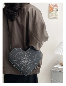 Détail d'un sac à bandoulière en forme de cœur avec broderie toile d'araignée blanche