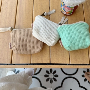 Pochettes cosmétiques en maille gaufrée marron, blanc et menthe sur une table en bois