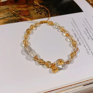 Close-up of citrine beaded bracelet with golden lotus pod charm and braided drawstring