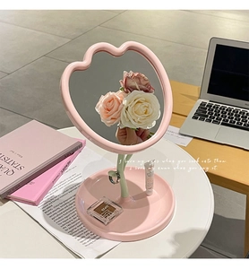 Pink apple-shaped desktop makeup mirror with integrated storage tray and green leaf detail