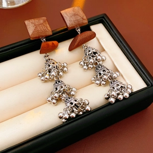 Detail of wooden geometric long drop earrings with silver multi-layer Jhumka bells