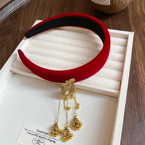 Close-up of red velvet headband featuring gold bell tassels and ethnic embroidery details