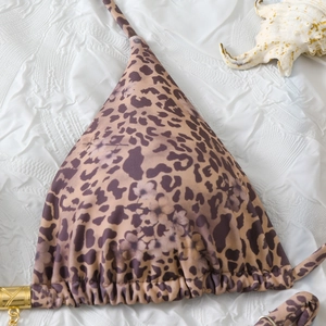 Detail of leopard print bikini top with gold buckle and halter tie on white background