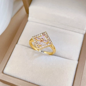 Macro shot of gold floral ring with pink zircon stones in a beige velvet jewelry box