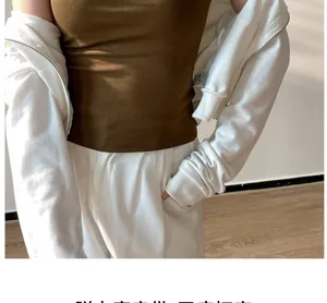 Detail of brown ribbed crop top paired with a white zip-up hoodie and trousers