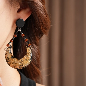 Close-up of vintage crescent resin earrings with gold foil flakes and colorful bead details