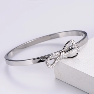 Detail of silver bow bangle featuring sparkling cubic zirconia on a white stone base