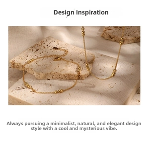 Detail of gold beaded chain necklace with lobster clasp and extension on stone background