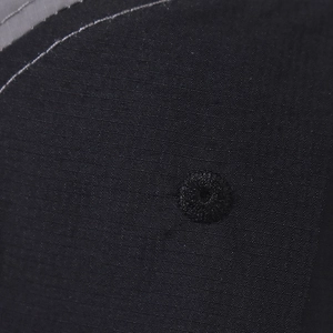 Macro shot of embroidered ventilation eyelet on black functional fabric outdoor baseball cap