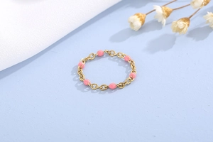 Dettaglio dell'anello a catena dorato con inserti di perle in resina rosa ovale
