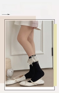 Detail of black Lolita crew socks featuring white lace trim and satin bow accents